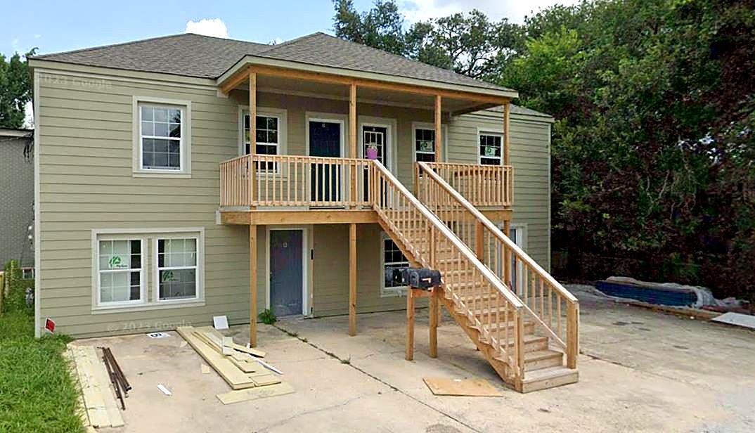 Same two-story duplex after renovation with new siding, porch and stairs