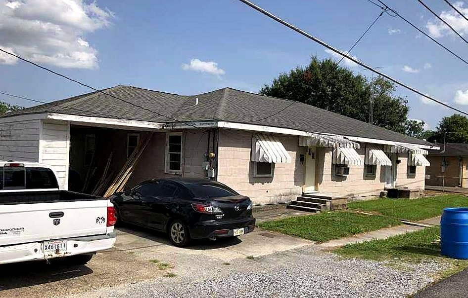 Single-story apartment units before renovation with old awnings and gravel lot