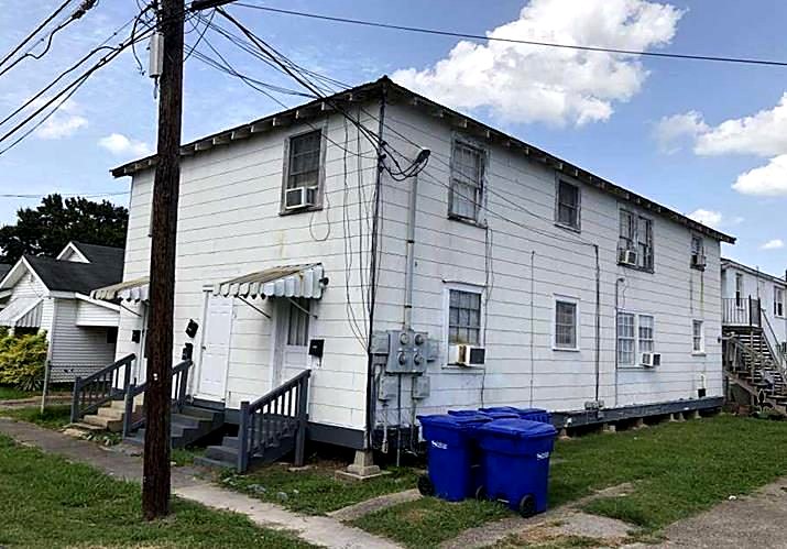 Two-story apartment building before renovation, worn siding and old window units