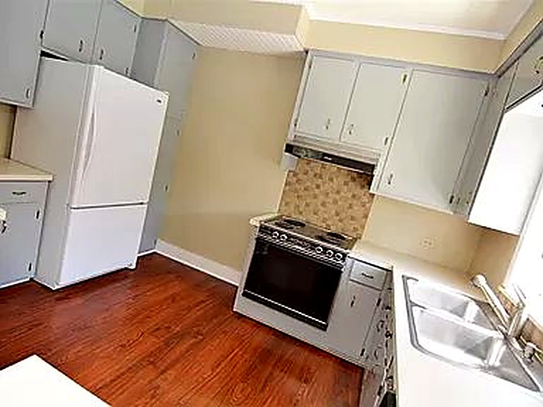 Kitchen before the remodel: older range and fridge, gray cabinets