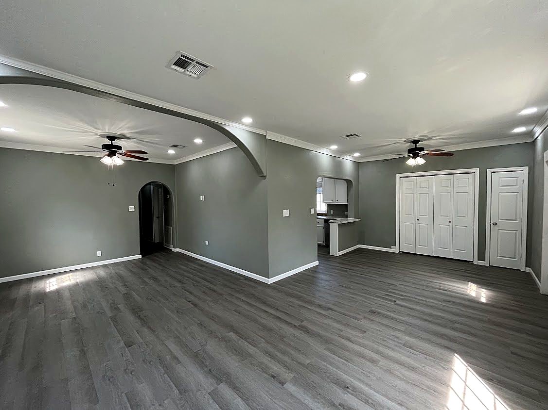 Open living area after the remodel: gray walls, white trim, recessed lights, new floors